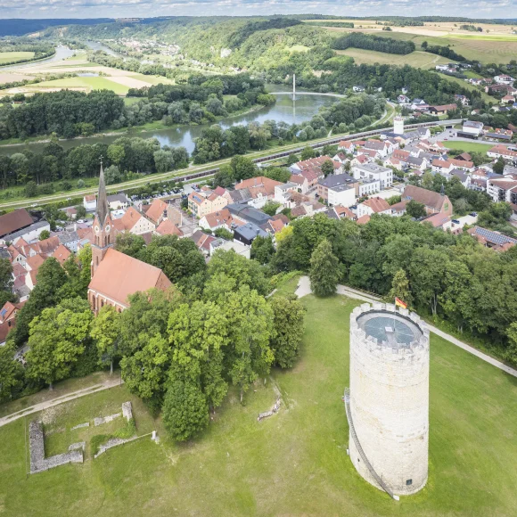 Luftaufnahme einer Stadt mit Kirche, Turm und Fluss in einer grünen Landschaft.